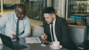 Two businessmen reviewing documents at a table.