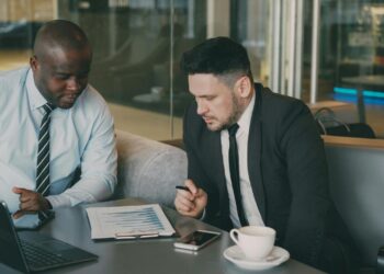 Two businessmen reviewing documents at a table.