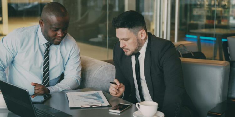 Two businessmen reviewing documents at a table.
