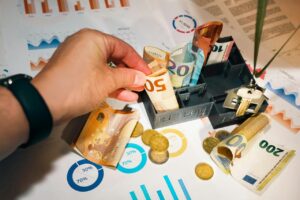 A person putting money into a miniature model house