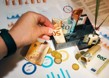 A person putting money into a miniature model house