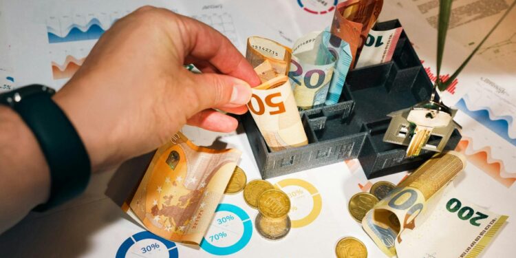 A person putting money into a miniature model house